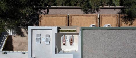 Un área de piscina en la azotea con sillones de descanso y un pequeño jardín.