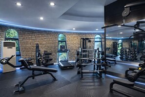 A gym with various exercise equipment, large windows, and a brick wall. - BaÅŸka Resort Bodrum - All inclusive (Bodrum)