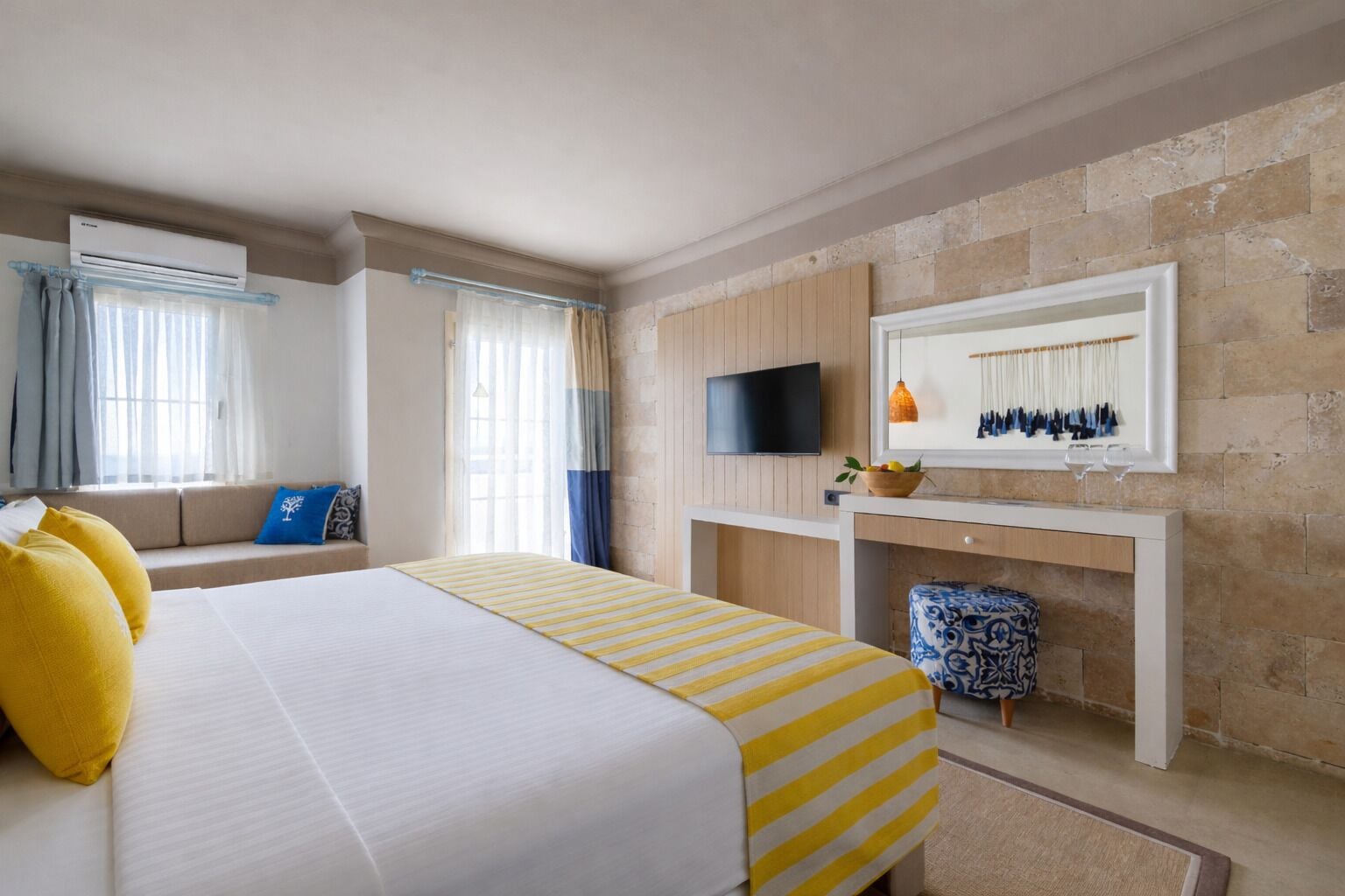Een hotelkamer met een bed, een televisie, een zithoek en een stenen muur.