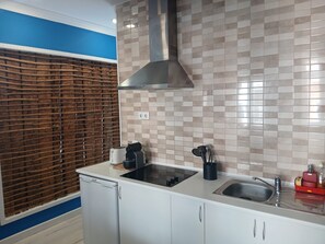 A modern kitchen with white cabinets, a stainless steel sink, a built-in stove, and a range hood. - Modern Apartment in Lisbon (Lisboa)