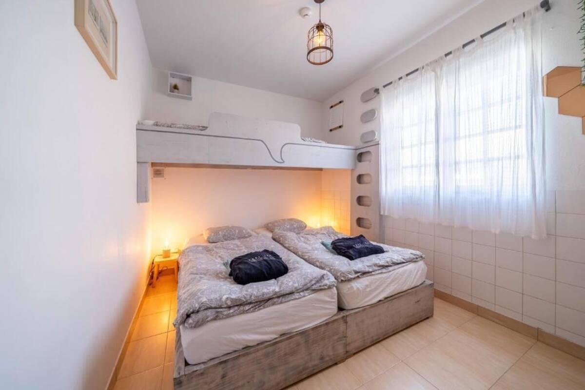 Una habitación con literas, una mesita pequeña y una lámpara colgante.