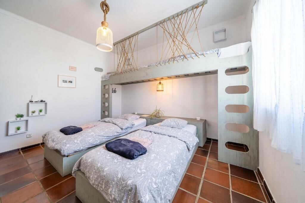 A room with two beds, a hanging light fixture, and a unique ceiling design.