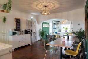 A spacious kitchen with a dining area, white cabinetry, and a variety of chairs. - SURFinn Algarve (Aljezur)