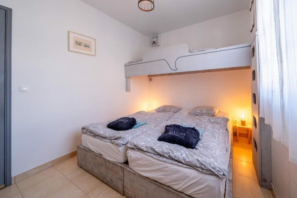 A small, compact room with bunk beds, a small table, and a wall-mounted shelf.