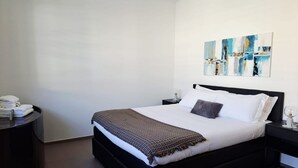 A modern bedroom with a large bed, a bedside table, a nightstand, and a wall-mounted abstract painting. - Just steps away from Parco Ciani (Mola Mimosa) (Lugano)