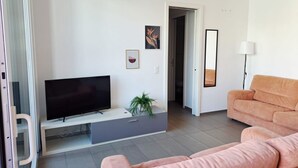 A modern living room with a flat-screen TV, a sofa, a potted plant, and artwork on the walls. - Just steps away from Parco Ciani (Mola Mimosa) (Lugano)