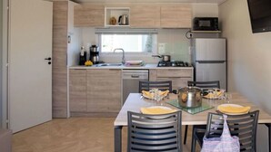 Una cocina compacta con mesa, sillas, microondas, refrigerador y ventana.