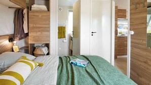 Un dormitorio con cama, un armario de madera y una puerta que da a un baño.