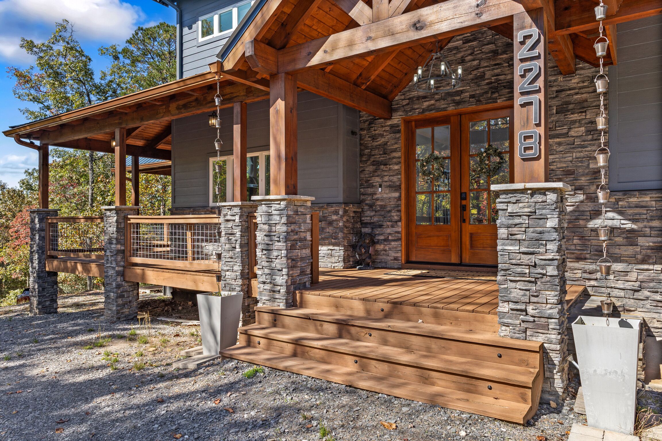 Ein modernes Haus mit Naturstein-Fassade, Holzterrasse und einer großen Eingangstür.
