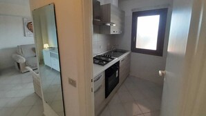 A compact kitchen with a gas stove, sink, and white cabinets. - ELEGANTE BILO D2 CASA SANDRA (Golfo di Marinella)