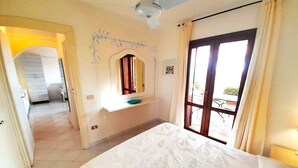 A bedroom with a bed, a window with curtains, a ceiling fan, and a bathroom visible in the background. - ELEGANTE BILO D2 CASA SANDRA (Golfo di Marinella)