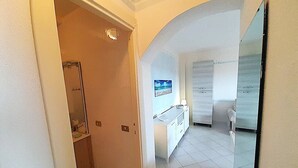 A hallway leading to a bathroom with a shower and a toilet, and a kitchen area with a refrigerator and a sink. - ELEGANTE BILO D2 CASA SANDRA (Golfo di Marinella)