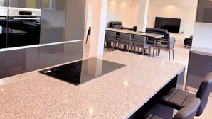 Una cocina moderna con una isla central, electrodomésticos integrados y un comedor con sillas y televisor.