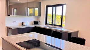 Una cocina moderna con una isla central, electrodomésticos integrados y un amplio ventanal que proporciona luz natural.