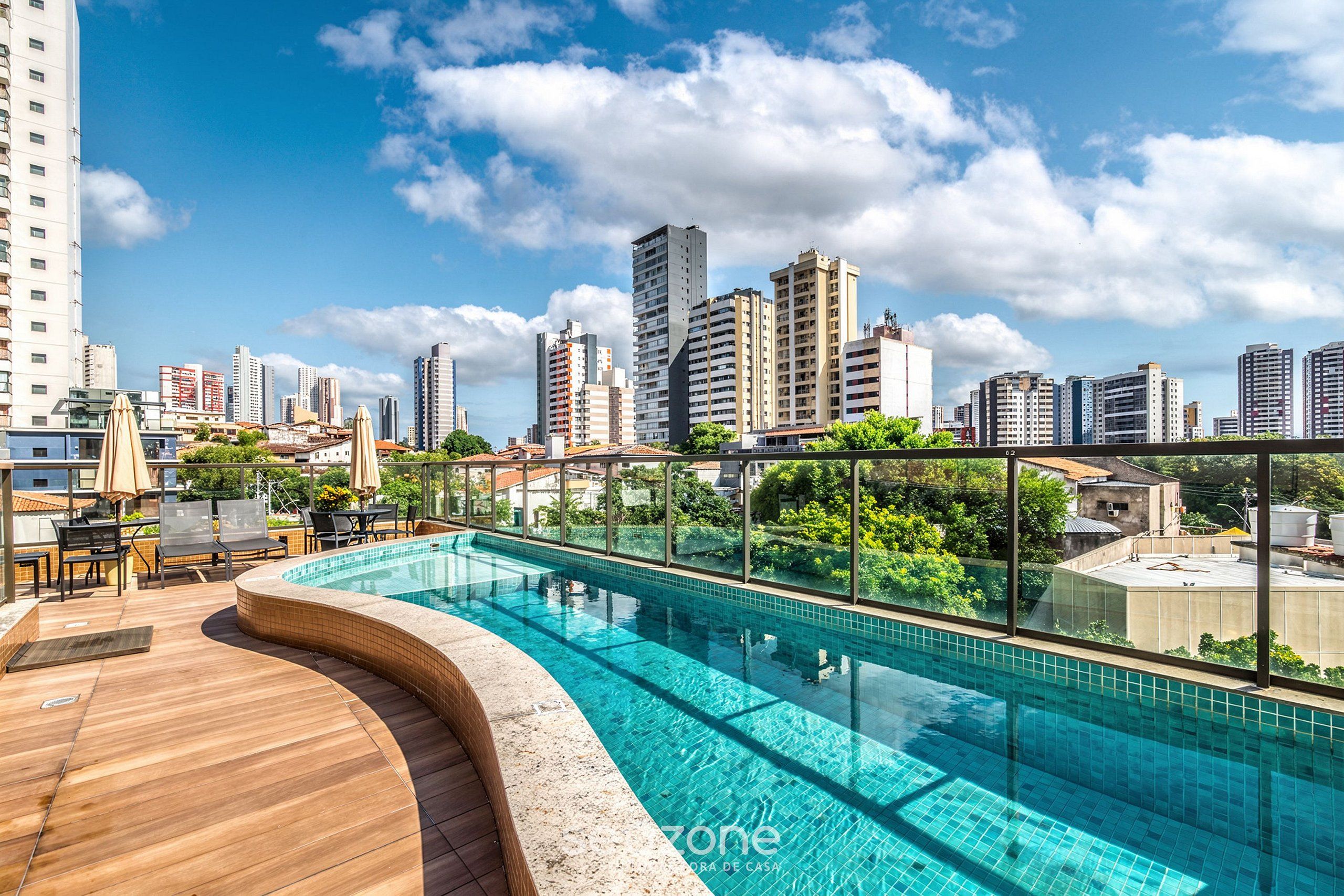Ein Pool auf dem Dach mit Blick auf die Stadtlandschaft, einer Holzterrasse und einem Sitzbereich im Freien.
