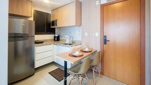 A compact kitchen with a stainless steel refrigerator, a microwave, and a sink. There is a dining table with two chairs and a small rug. - Studio in Condo w/ Pool and Gym Ftw1106 (Salvador)