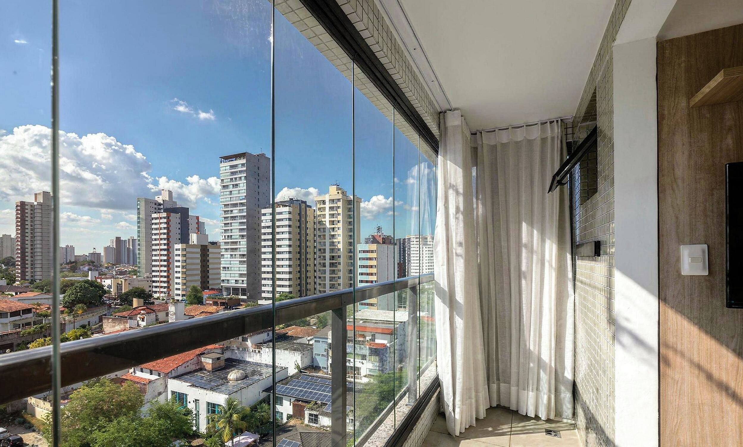 Un balcon avec vue sur la ville, une porte en bois et une fenêtre avec des rideaux.
