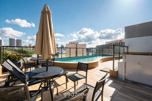 A rooftop pool area with lounge chairs, a table, and an umbrella. - Studio in Condo w/ Pool and Gym Ftw1106 (Salvador)
