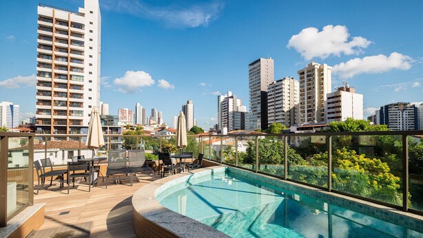 A rooftop pool area with a view of a cityscape, including high-rise buildings and a clear sky. - Studio in Condo w/ Pool and Gym Ftw1106 (Salvador)