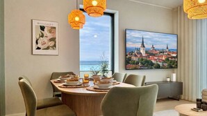 Uma área de refeições moderna com mesa redonda, cadeiras estofadas em verde e luminárias de vime suspensas.
