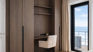 Quarto com uma cama grande, uma cadeira, um guarda-roupa e varanda com vista.