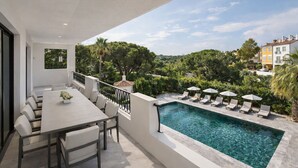 Un espacio exterior moderno con piscina, sillas de descanso y una mesa de comedor.