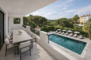 Ein moderner Außenbereich mit Pool, Liegestühlen und einem Esstisch.