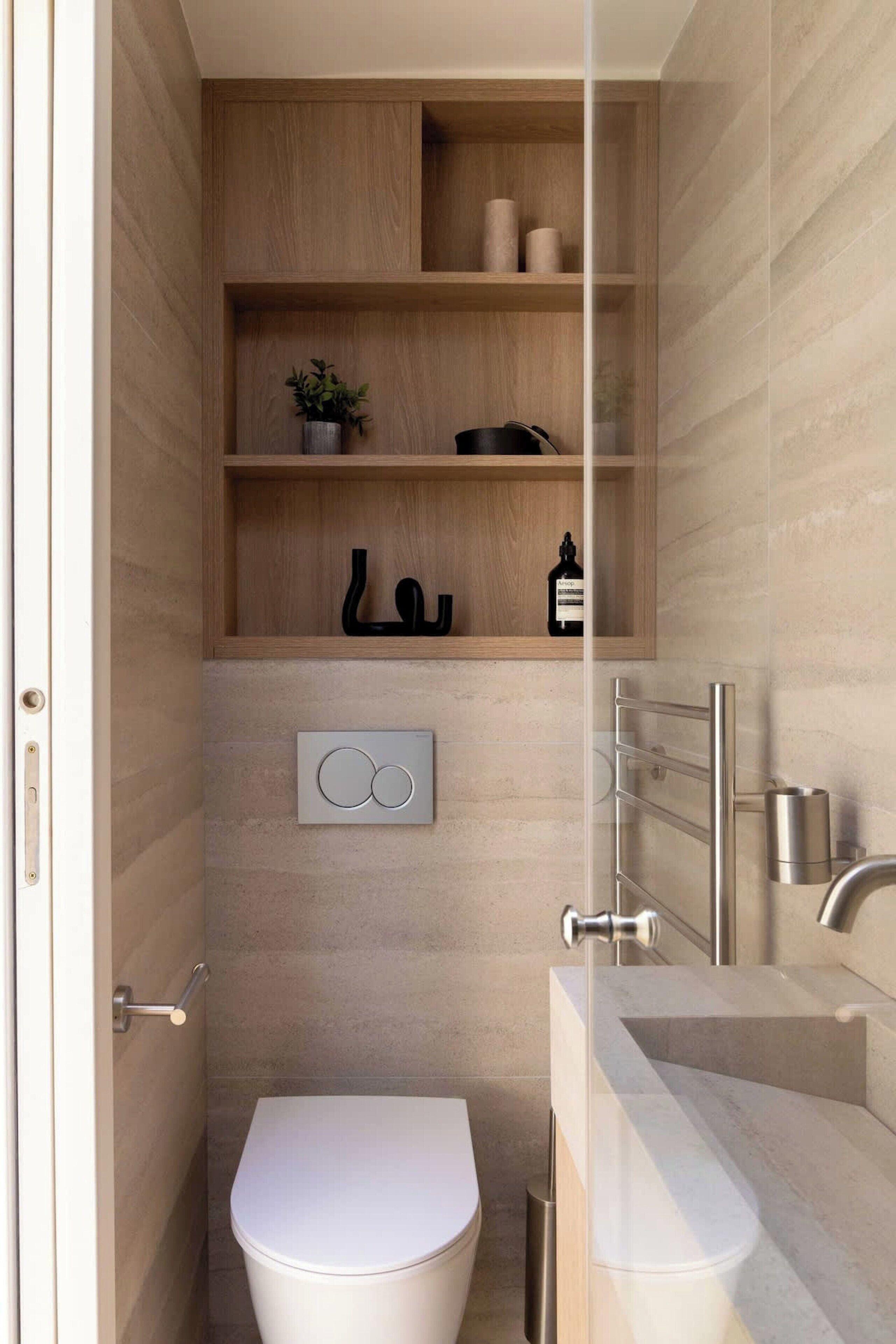 A modern bathroom with a toilet, a sink, and a shelf with toiletries.