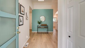 A hallway with a teal accent wall, a round mirror, and framed pictures on the left. - Charming Sunset Park Stay Near Parks & Greenbelt (Boise)
