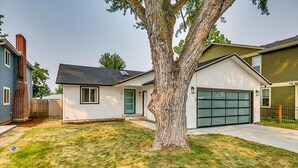 A residential house with a garage, a lawn, and a large tree in the front yard. - Charming Sunset Park Stay Near Parks & Greenbelt (Boise)