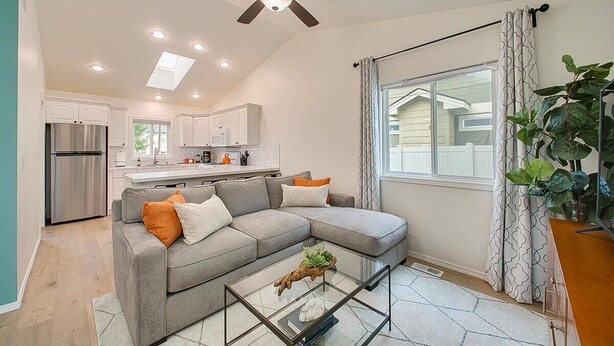 A modern living room with a grey sectional sofa, a glass coffee table, and a ceiling fan. - Charming Sunset Park Stay Near Parks & Greenbelt (Boise)