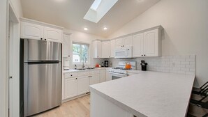 A modern kitchen with white cabinetry, stainless steel appliances, and a large island. - Charming Sunset Park Stay Near Parks & Greenbelt (Boise)
