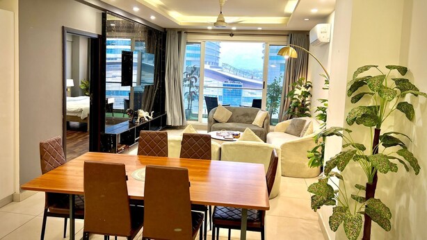 A modern living room with a dining area, large windows, and a view of a cityscape. - Said's Suites Elysium tower opposite to centaurus mall Islamabad (Islamabad)