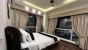 Una habitación de hotel moderna con una cama grande, un escritorio y vistas de la ciudad de noche.