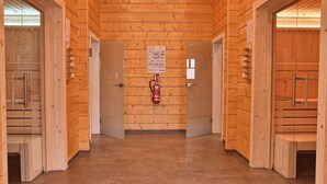 Un pasillo de madera con puertas a ambos lados, un extintor montado en la pared y un cartel con instrucciones de emergencia.