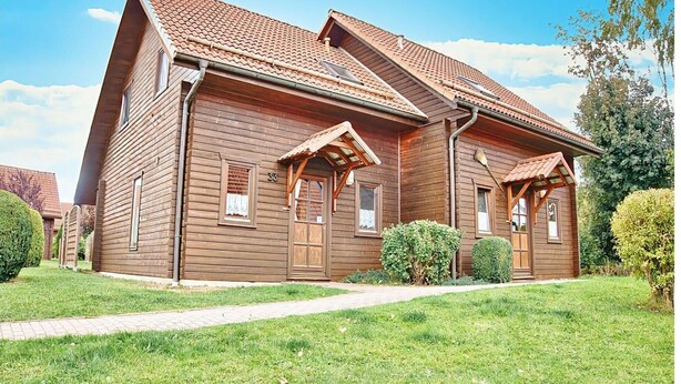 Una casa de madera con techo inclinado, porche delantero y un pequeño jardín.
