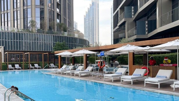 A swimming pool with lounge chairs and umbrellas, surrounded by high-rise buildings. - Luxurious 2BD in Address Residences Opera Walk to Dubai Mall & Burj Khalifa (Dubai)