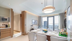 A modern dining area with a high table set for four, a view of the city, and a kitchen with a microwave and coffee maker. - Luxurious 2BD in Address Residences Opera Walk to Dubai Mall & Burj Khalifa (Dubai)