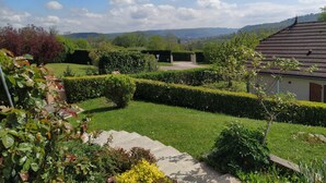 A well-maintained garden with hedges, a clear sky, and distant mountains. - Summer rental Villa & pool Lons le Saunier (Courlans)