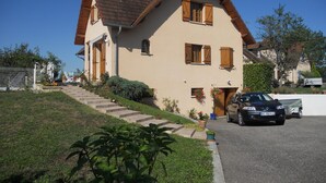 A two-story house with a sloped roof, a front entrance, and a car parked in the driveway. - Summer rental Villa & pool Lons le Saunier (Courlans)