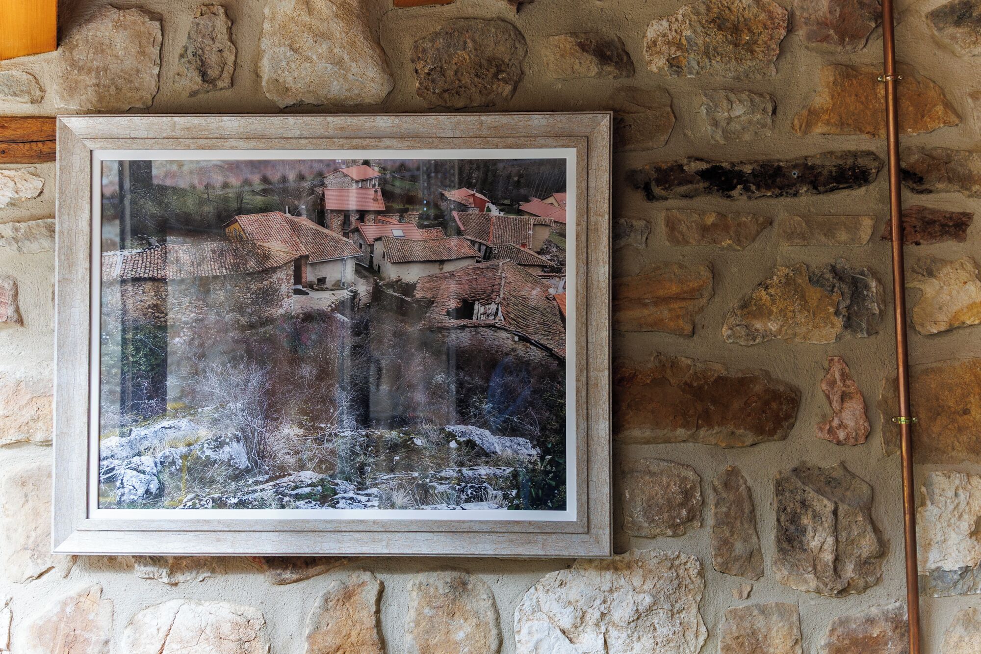 Une photographie encadrée représentant un village avec des bâtiments traditionnels et un mur de pierre en arrière-plan.