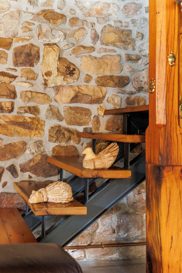 Una escalera con escalones de madera y un muro de piedra.