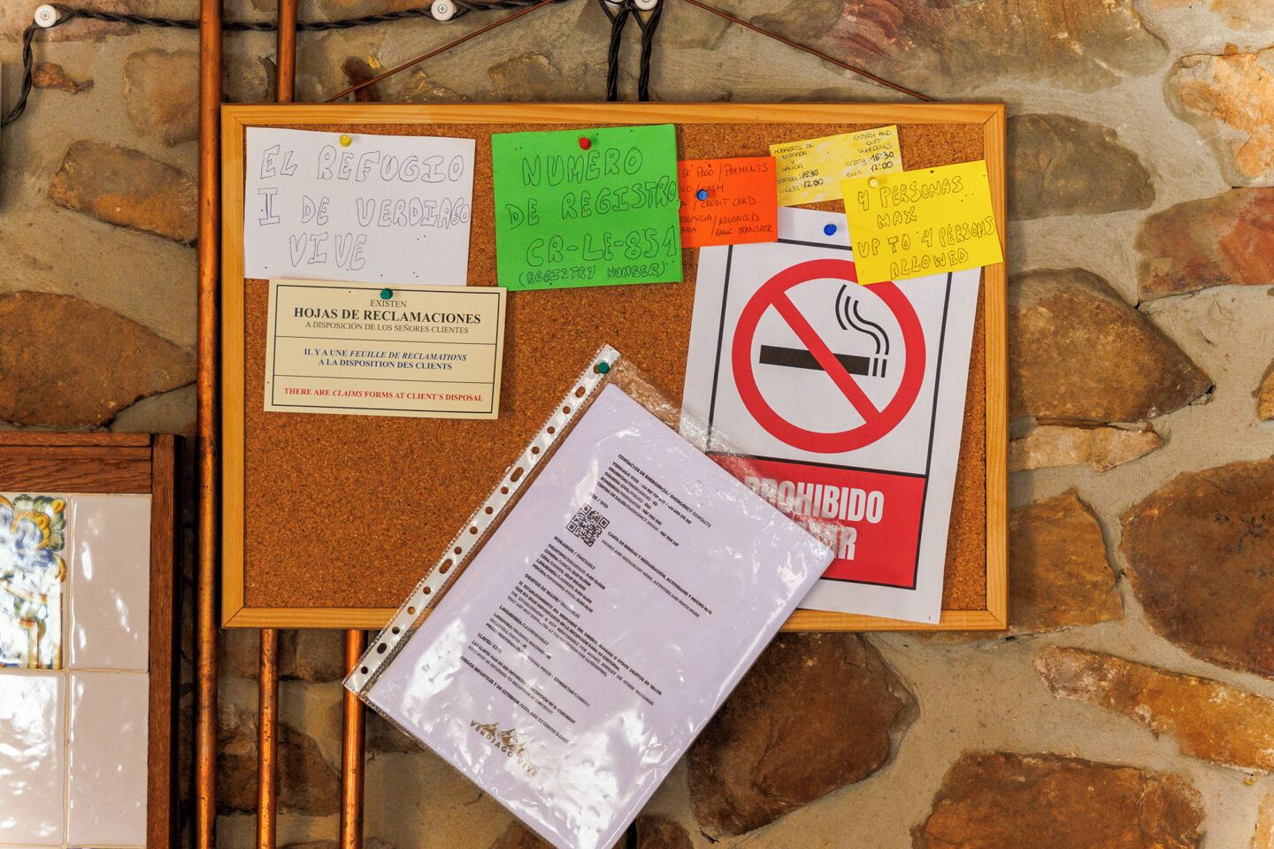 A corkboard with various notes, a no-smoking sign, and a plastic bag with printed text.