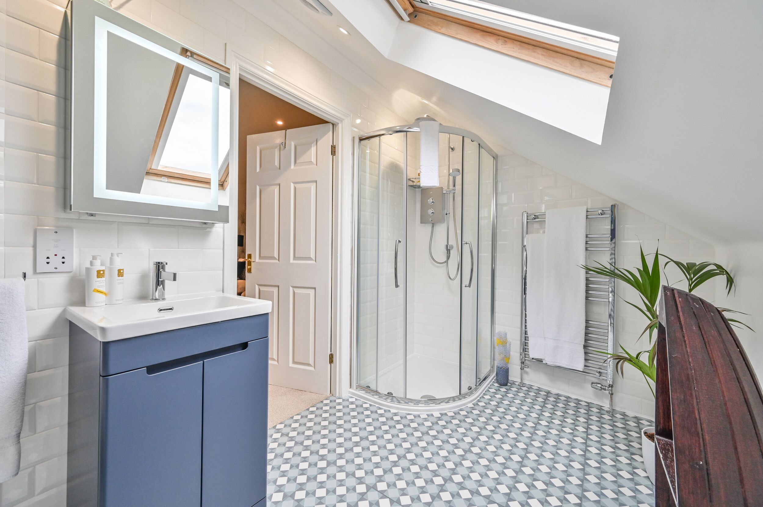 A modern bathroom with a glass shower enclosure, a vanity with a sink, and a tiled floor.