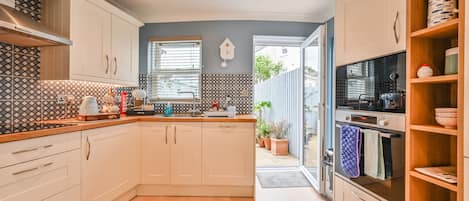 A modern kitchen with white cabinets, a built-in oven, and a large window.
