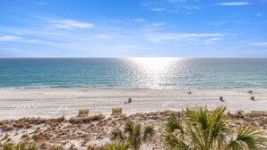 Una spiaggia con cielo sereno, mare calmo e alcune sedie a sdraio.