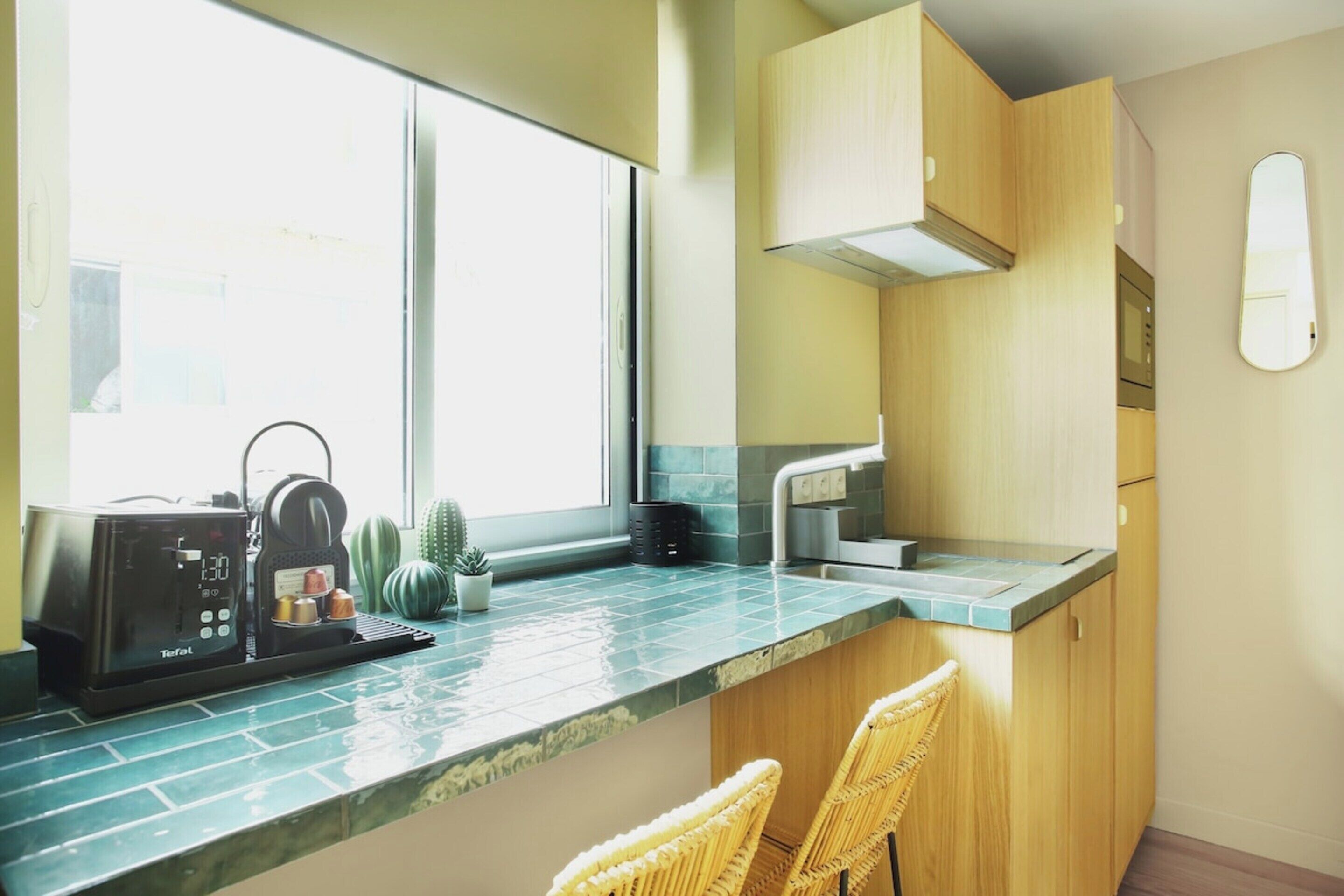 A kitchen with a coffee machine, a window, and two wicker chairs.