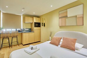 Ein modernes Hotelzimmer mit einem Bett, einer kleinen Küchenzeile und einem Essbereich.