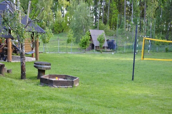 A grassy outdoor area with a wooden structure, a fire pit, and a soccer goal. - Summer cottages in Kashubia. (Dąbie)