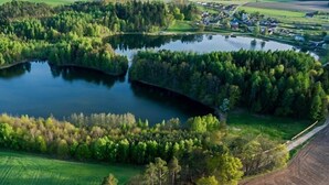 An aerial view of a lake surrounded by dense forests and a small village. - Summer cottages in Kashubia. (Dąbie)
